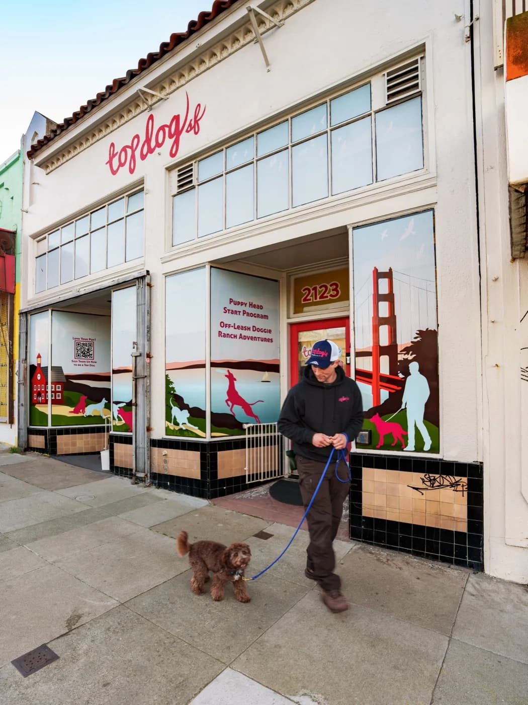 A walker heading out with a doodle puppy on leash from the Taraval Street storefront